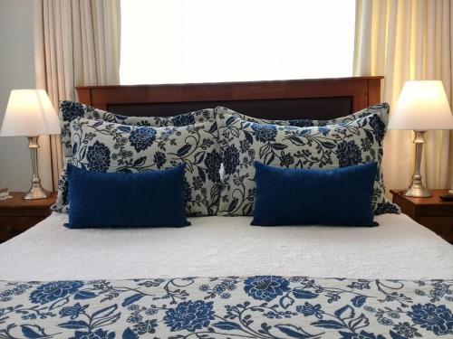 a bed with blue and white pillows and two lamps at Hotel Puerta del Lago in Puerto Varas