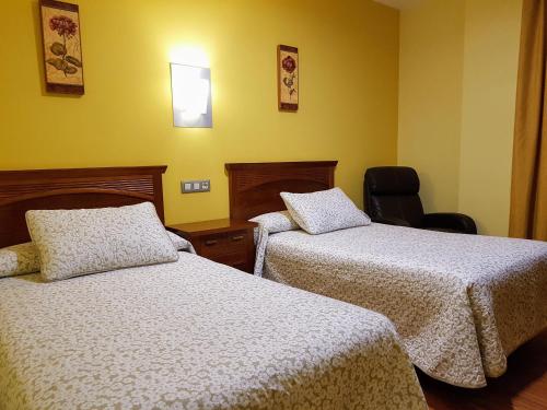 a hotel room with two beds and a chair at Hotel Reina Isabel in Medina del Campo