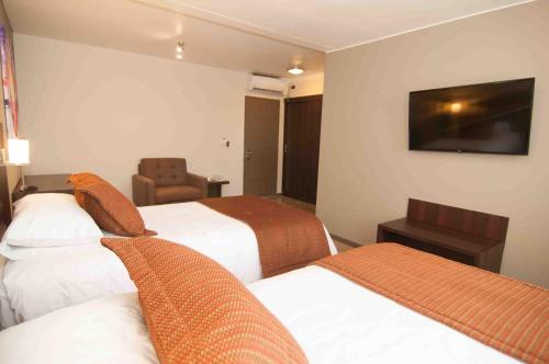 a hotel room with two beds and a television at Hotel Manso de Velasco in San Fernando