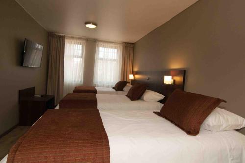 a hotel room with three beds with brown pillows at Hotel Manso de Velasco in San Fernando