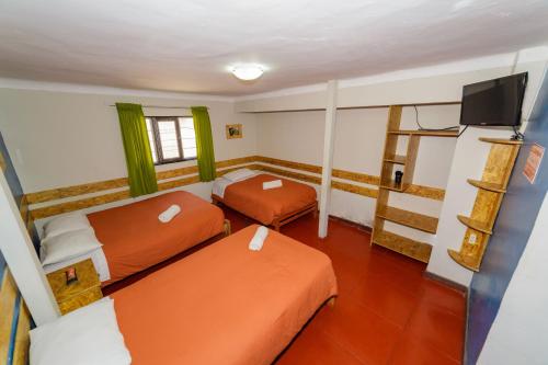 Habitación pequeña con 2 camas y TV. en Ukukus Hostel, en Cusco