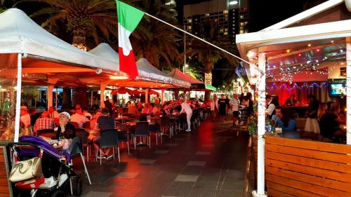a crowd of people sitting at an outdoor restaurant at night at APR Private SUITES MOROCCAN by the Beach in Gold Coast