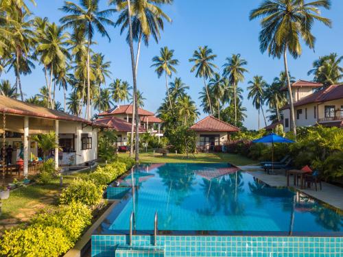 an image of a swimming pool at a resort with palm trees at Lanka Beach Boutique Bungalows & Grand Villa in Tangalle