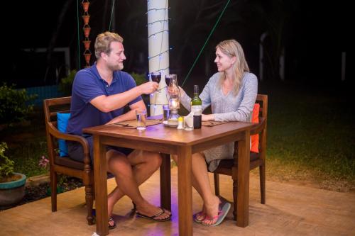 a man and woman sitting at a table with wine glasses at Lanka Beach Boutique Bungalows & Grand Villa in Tangalle