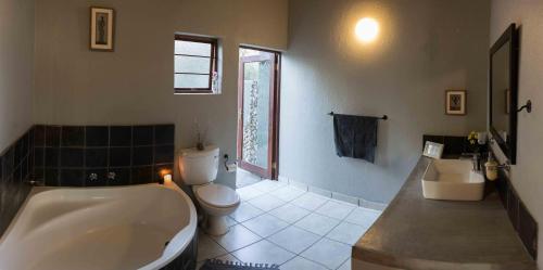 a bathroom with a tub and a toilet and a sink at The Bush House in Hoedspruit