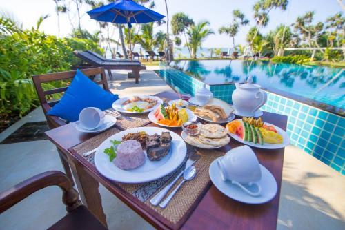 a table with plates of food next to a pool at Lanka Beach Boutique Bungalows & Grand Villa in Tangalle