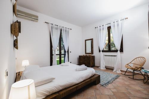 Un dormitorio blanco con una cama grande y dos ventanas. en LuminHouse Villa Mondello, en Mondello