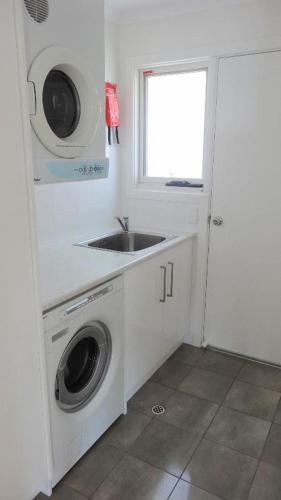 a kitchen with a sink and a washing machine at Millpond. in Penneshaw