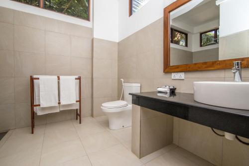 a bathroom with a sink and a toilet and a mirror at Lanka Beach Boutique Bungalows & Grand Villa in Tangalle