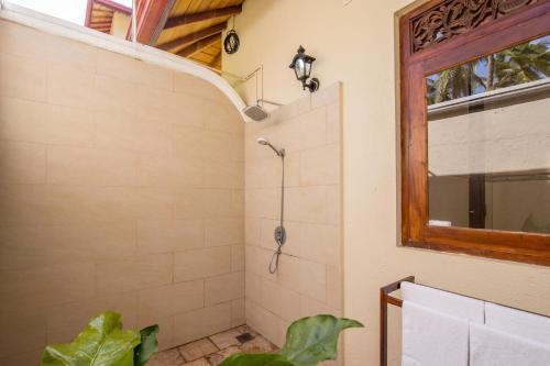 a bathroom with a shower with a plant in it at Lanka Beach Boutique Bungalows & Grand Villa in Tangalle
