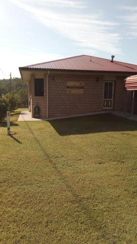 a brick house with a grass yard in front of it at GOLDEN LACE B&B in Sarina