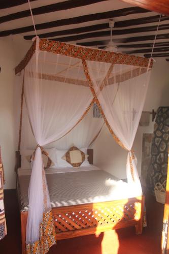 a bedroom with a canopy bed with curtains at Mapeni Lodge in Kidenge