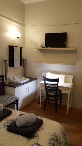 Cette chambre comprend un lit et un bureau avec un lavabo. dans l'établissement Pretoria Inn, à Pretoria