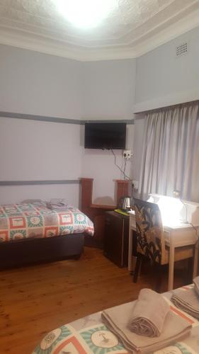 a bedroom with a bed and a desk and a table at Pretoria Inn in Pretoria