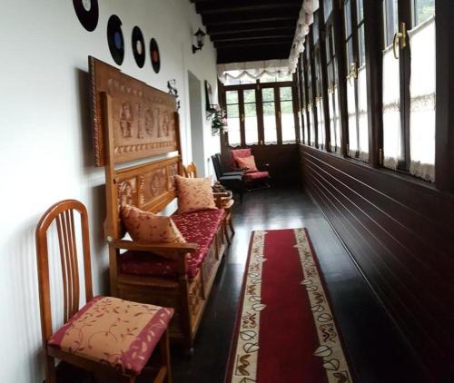 a hallway with chairs and windows and a red rug at Hotel Rural Palacio de Galceran in Sotiello