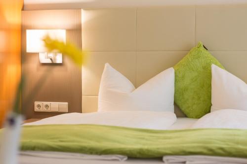 a bed with white pillows and green pillows at City Hotel Freiburg in Freiburg im Breisgau