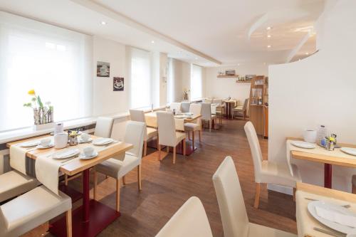 a restaurant with wooden tables and white chairs at City Hotel Freiburg in Freiburg im Breisgau