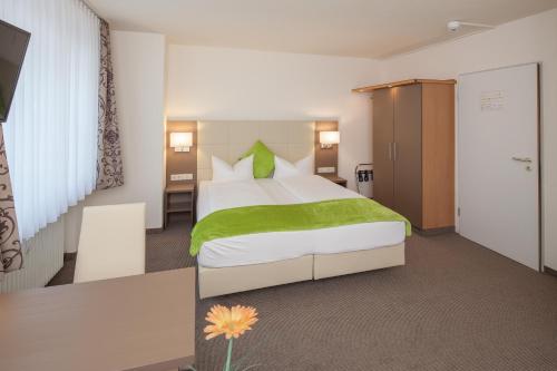 a bedroom with a large bed with a green blanket at City Hotel Freiburg in Freiburg im Breisgau