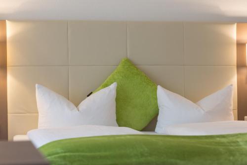 a bed with green and white pillows on it at City Hotel Freiburg in Freiburg im Breisgau