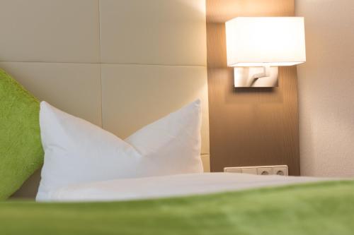 a bed with a white pillow and a lamp at City Hotel Freiburg in Freiburg im Breisgau