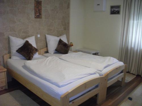 Schlafzimmer mit einem Bett mit weißer Bettwäsche und Kissen in der Unterkunft Ferienwohnung Fischer mit Balkon in Hambach