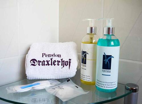 a glass table with two bottles of disinfectants and a towel at Pension Draxlerhof in Neuschönau