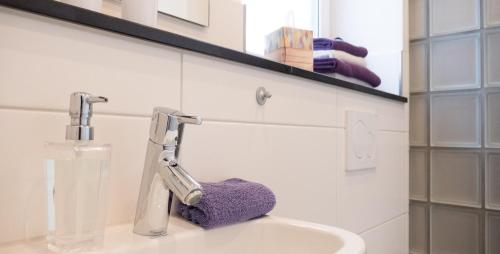 ein Badezimmer mit einem Waschbecken und einem lila Handtuch darauf in der Unterkunft Freches Wohnen - Apartment in Lindau