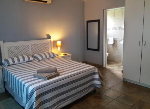 a bedroom with a large bed and a bathroom at Umsinsi Cottage in Hluhluwe
