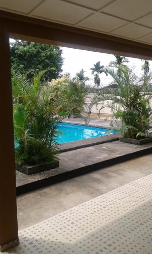 Blick auf den Pool durch ein Fenster in der Unterkunft Residence Japoma in Douala