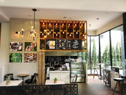 a restaurant with a bar with a person behind the counter at Astra Suites Central in Chiang Mai