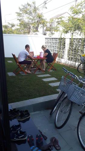 two people sitting at a table in a yard with shoes at Melody Boutique Villa Hoi An in Hoi An