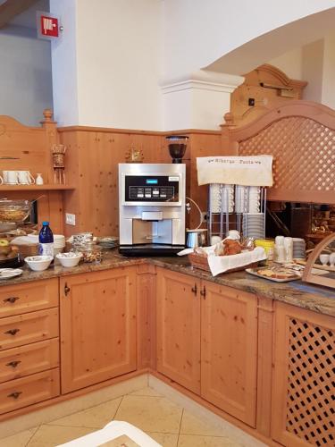 a kitchen with wooden cabinets and a microwave oven at Hotel Garnì posta in Forno di Zoldo