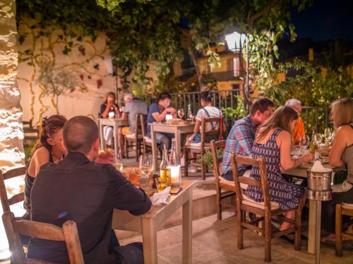 people sitting around a wooden table at Auberge De Tourrettes in Tourrettes-sur-Loup