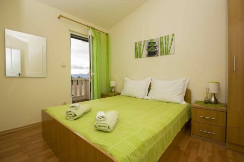 a bedroom with a green bed with towels on it at Apartmani Sani Bol in Bol