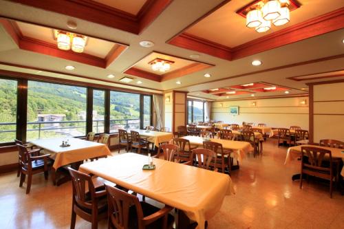 a dining room with tables and chairs and windows at Zao Plaza Hotel in Zaō Onsen