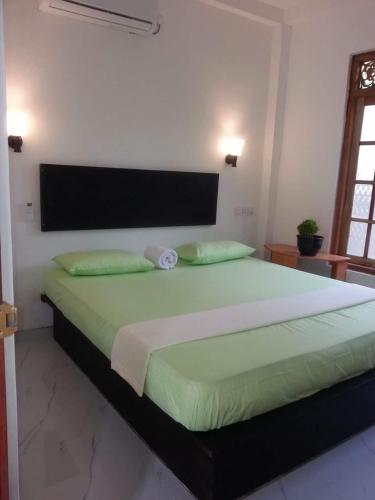 a bedroom with a large bed with green sheets at Monara Backpacker Inn Unawatuna in Unawatuna