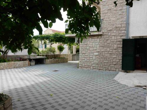a courtyard with a stone wall and a building at Apartmani Sani Bol in Bol