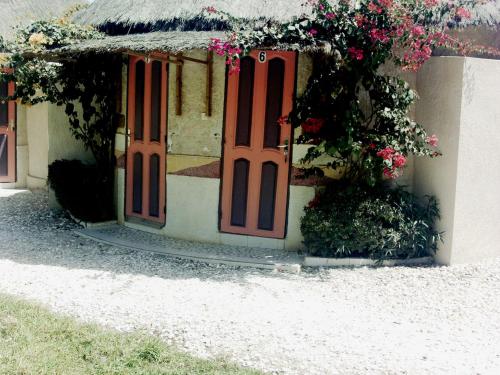 a house with red doors and flowers on it at Le Chamama in Niaga