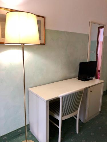 a desk with a laptop on it with a lamp at Hotel Internazionale Gorizia in Gorizia