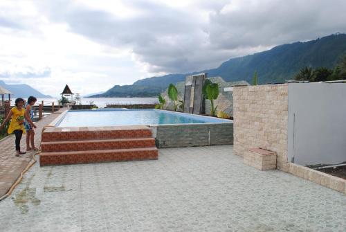 a child is walking next to a swimming pool at Toba Village Inn in Tuk Tuk
