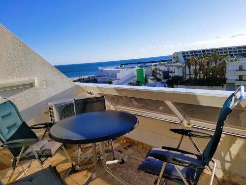 a table and chairs on a balcony with a view of the ocean at CapSexy Heliopolis Sea View Naturist Village in Cap d'Agde