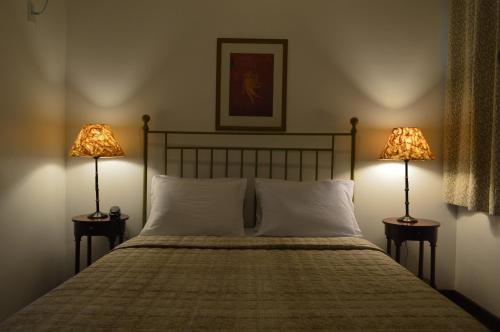 a bedroom with a bed with two lamps on both sides at Don Quixote Pousada in Tiradentes