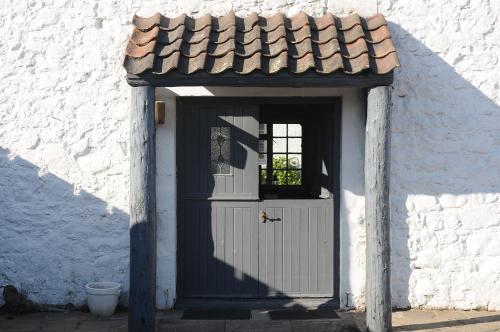 a white building with a door with a roof at The Inn At Lathones in St. Andrews