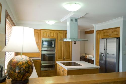 a kitchen with wooden cabinets and stainless steel appliances at Ainslie Manor Guest House in Redcliffe