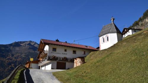 Un pequeño edificio blanco en una colina con una casa. en Alpenchalet Farst, en Umhausen