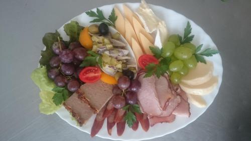a plate of food with meat and cheese and grapes at Willa Zamkowisko in Gołubie