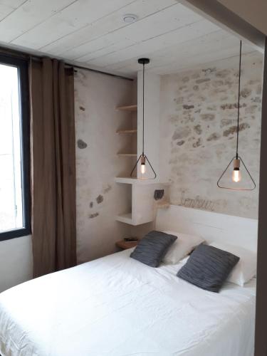 une chambre avec un lit blanc avec deux oreillers dessus dans l'établissement La Terrasse La Tremblade, à La Tremblade