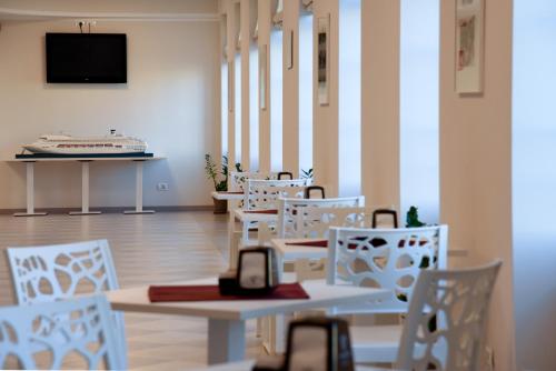a room with white chairs and tables and a tv at Nuovo Albergo Operai in Monfalcone