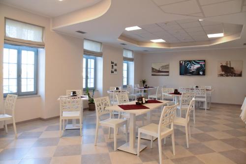 a room with white tables and chairs and windows at Nuovo Albergo Operai in Monfalcone