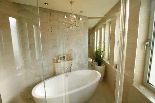 baño con bañera blanca grande y lámpara de araña en Apartments Marer, en Trogir